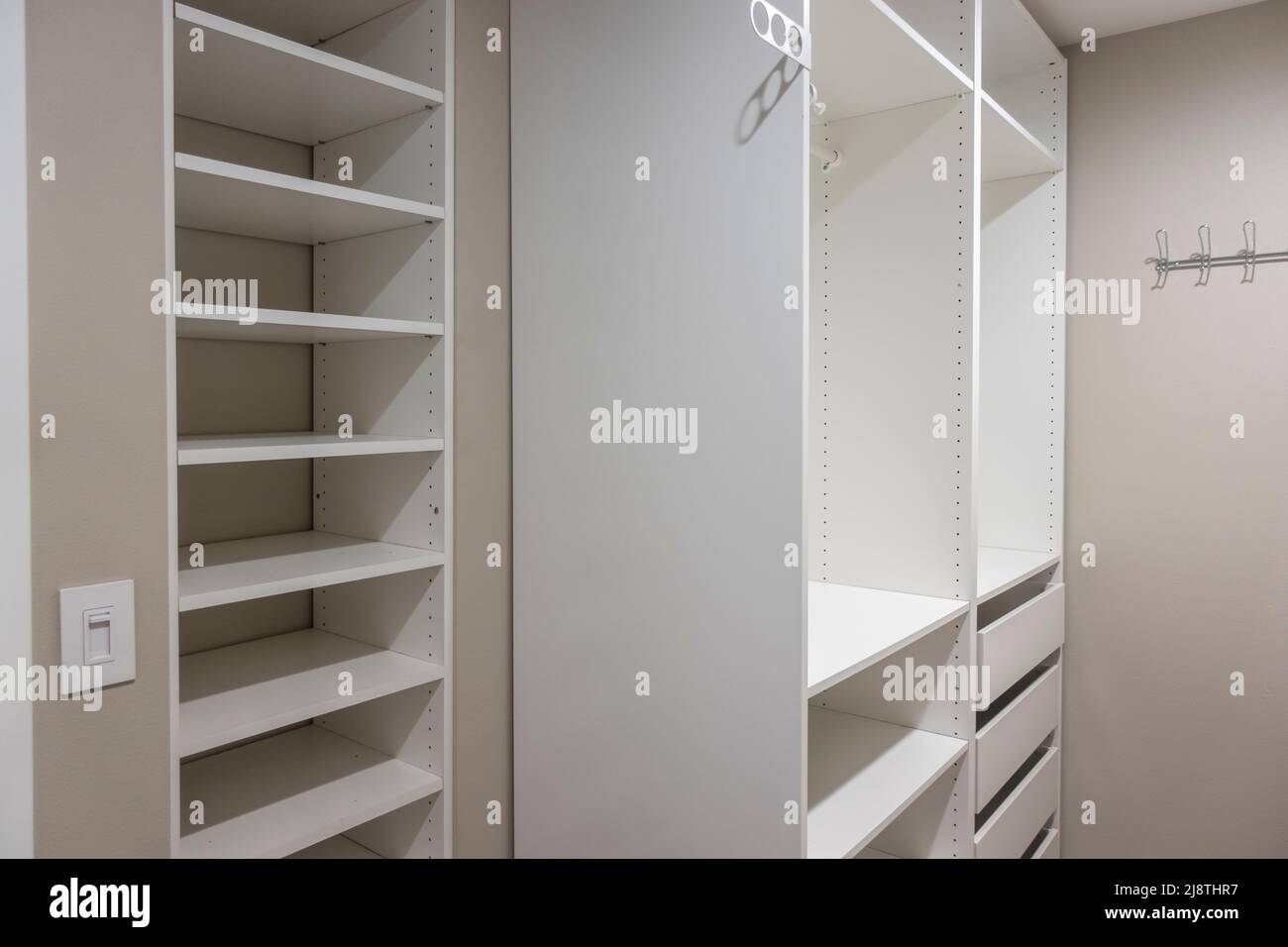 View of tall, white and drawers inside a narrow walk in closet inside a master bedroom
