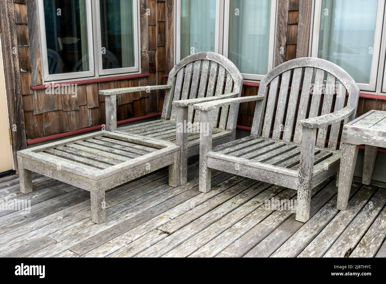 Angled view of wooden deck chairs at a cliffside cabin by the sea in