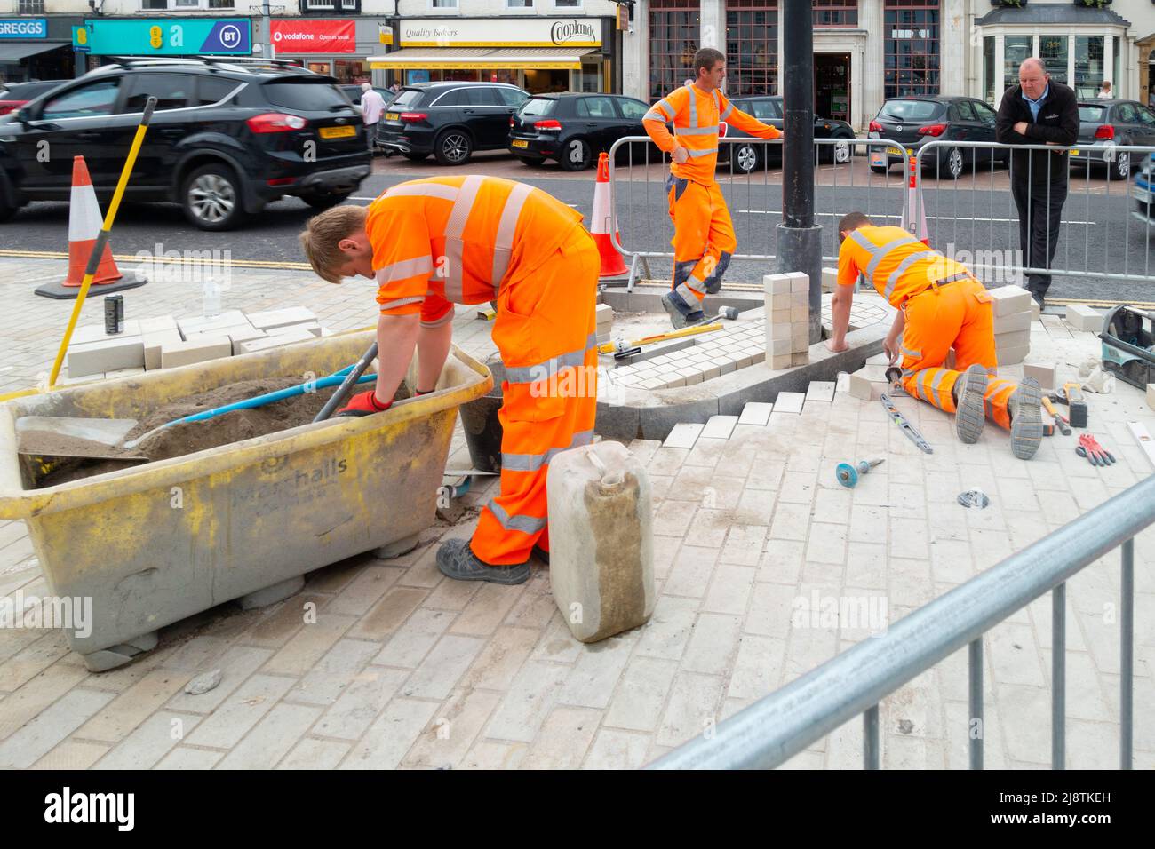 Workmen laying a new block pavement surface in the High Street of Northallerton North Yorkshire England Stock Photo
