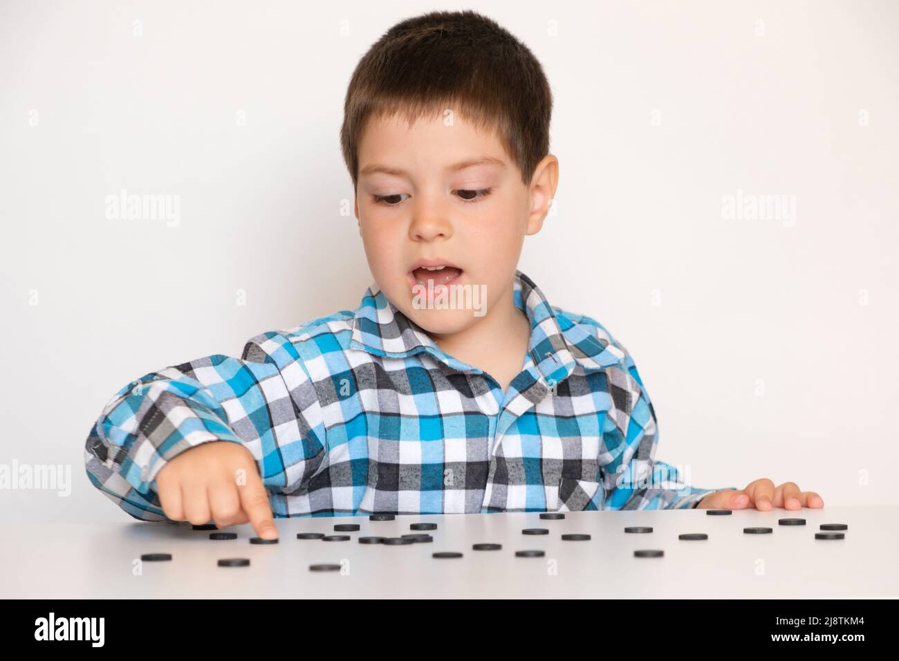 A 4-year-old boy is learning to count, teaching black numeracy chips for preschoolers Stock Photo