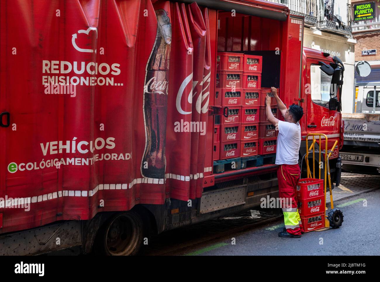A delivery truck worker offloads American soft drink brand Coca-Cola goods in Spain. Stock Photo