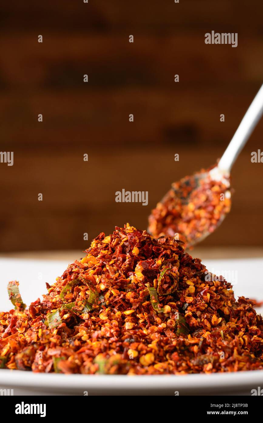 red chili sambol or spicy condiment on a plate with a spoon, made with chili peppers and maldive fish, taken in shallow depth of field, closeup view Stock Photo