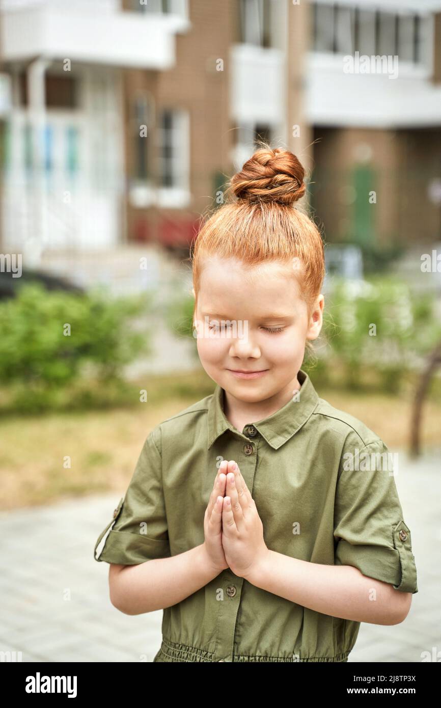 Kid at playground. Pretty face. Cute school child. Active vacation. Red hair. Small people. Summer freedom. Happy children concept. Lifestyle action. Namaste hand pose Stock Photo