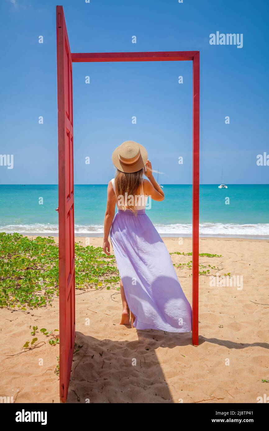 Tropical travel vacation. Traveler woman in red door on beach to turquoise sea Stock Photo