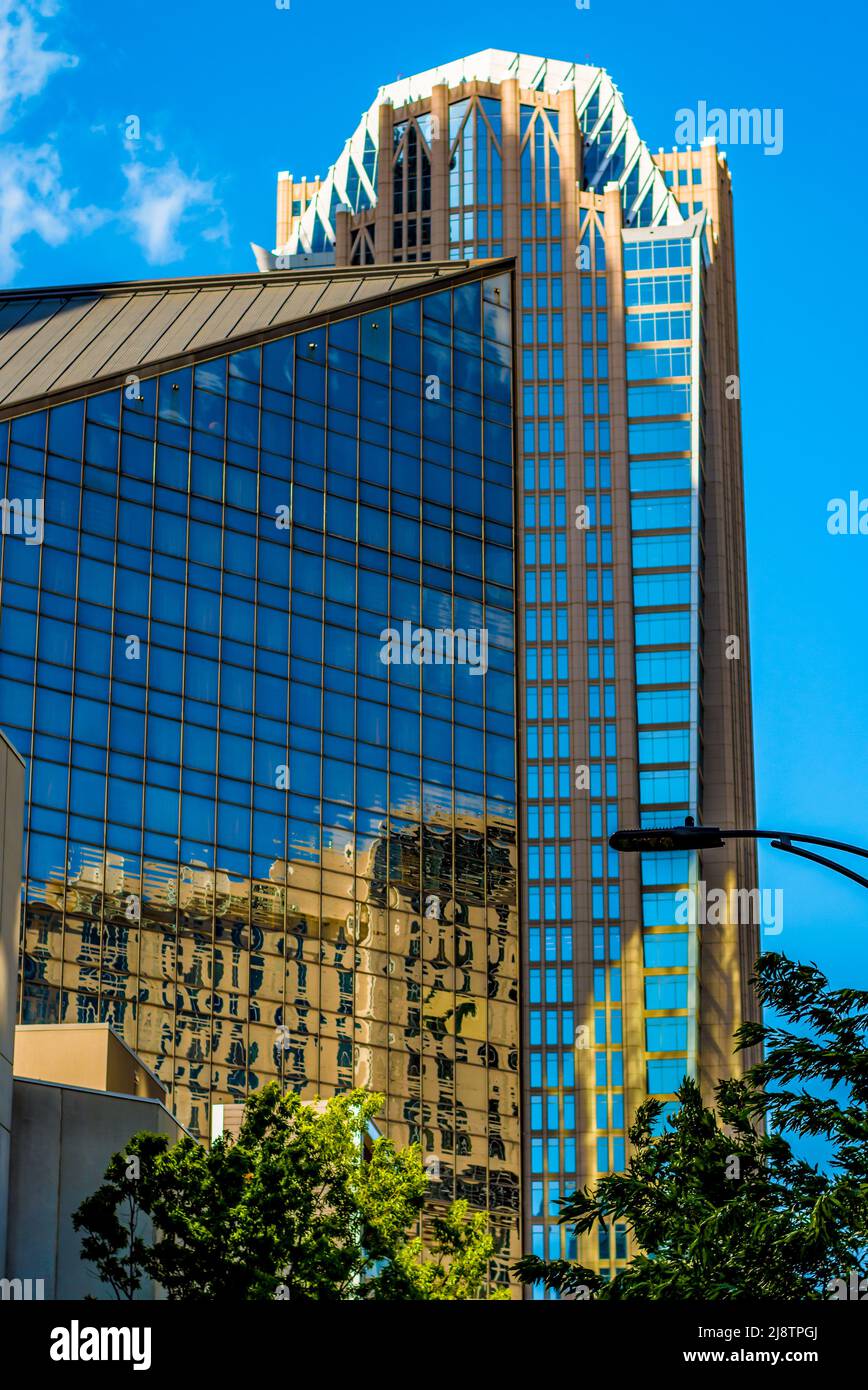 Hearst Building in uptown Charlotte, North Carolina on a bright sunny day with brilliant blue sky, a few wispy clouds and  reflections in windows. Stock Photo