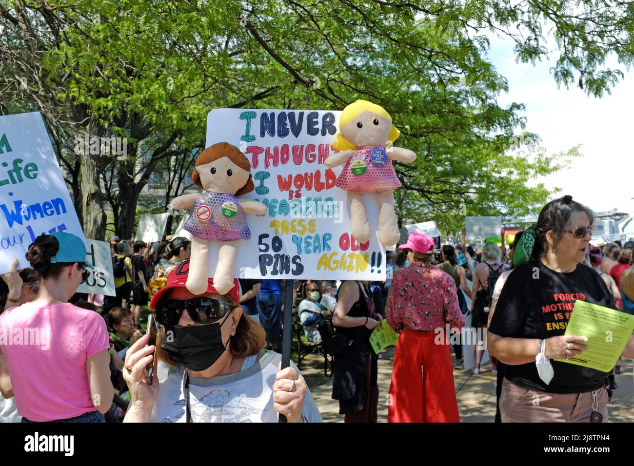 Older woman talks on the phone holding a retro abortion rights sign during the May 14, 2022 rally in Cleveland, Ohio in response to Roe versus Wade. Stock Photo