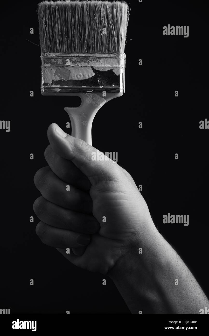 Paint brush in hand on a black and white image Stock Photo - Alamy