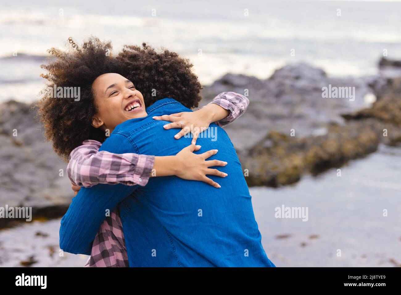 Cheerful young african american woman hugging afro boyfriend at beach ...