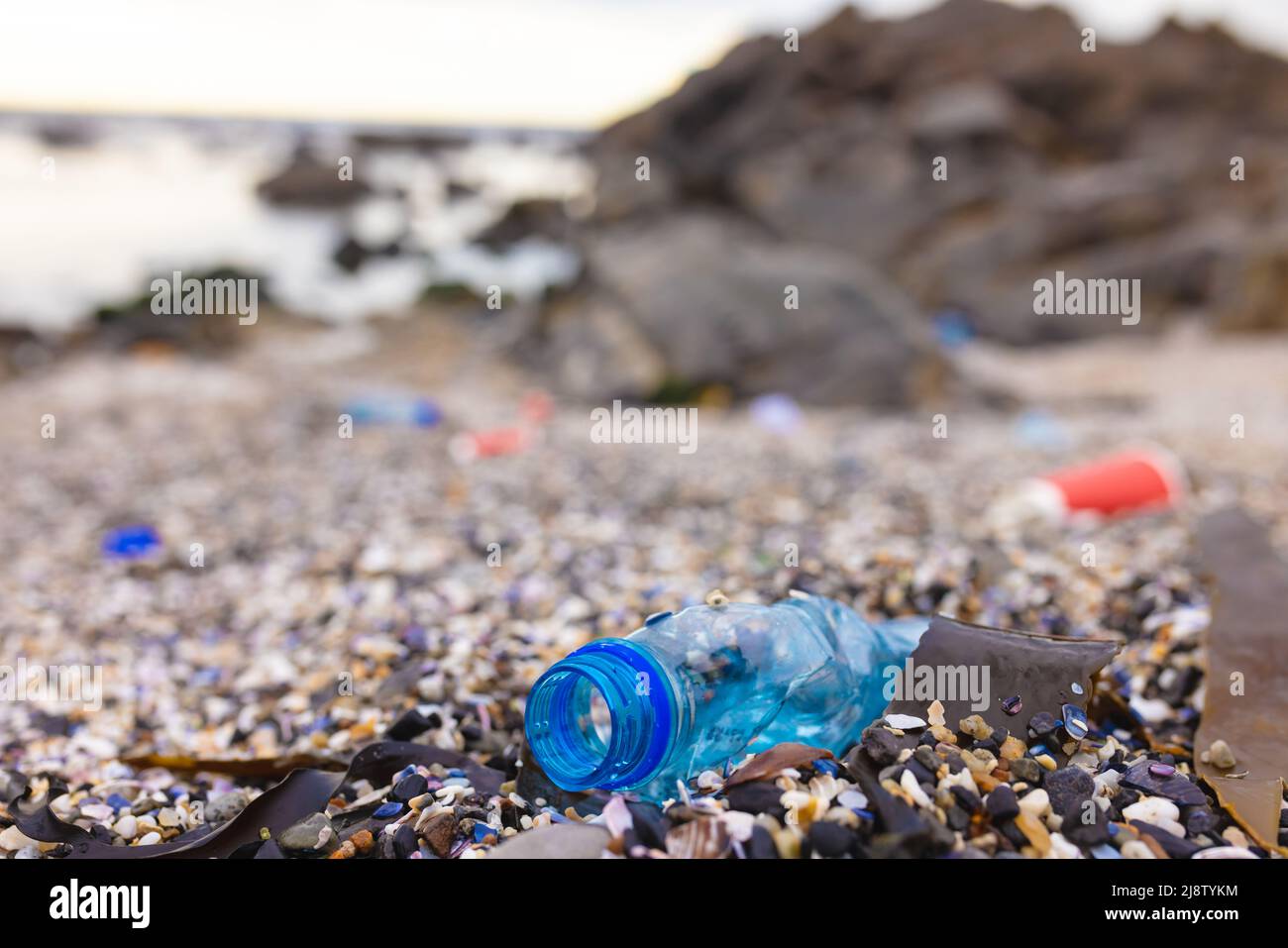 Close-up of blue plastic bottle on small pebbles at coastline Stock Photo