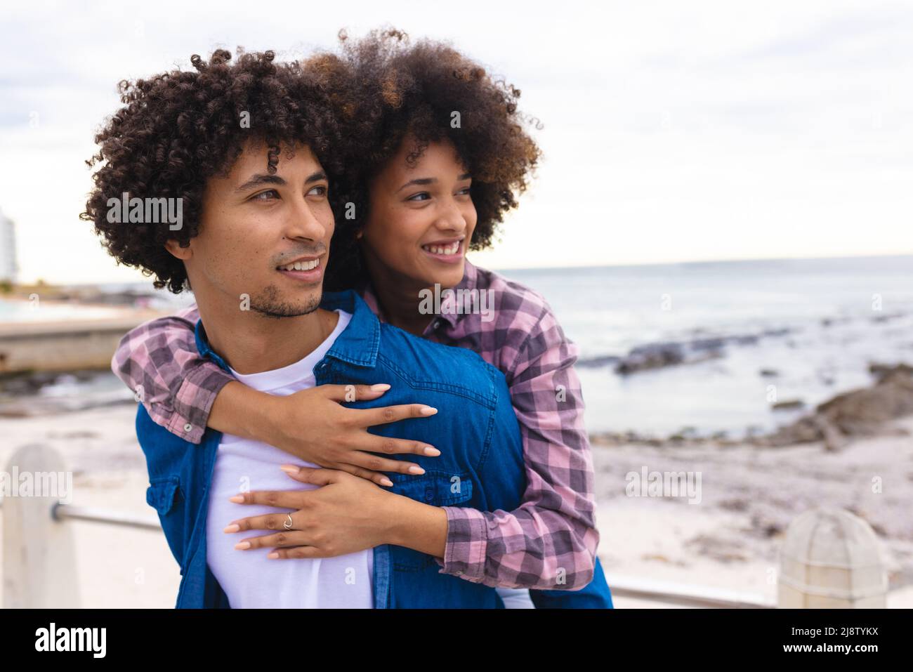 Afro young woman hugging african american boyfriend from behind while ...