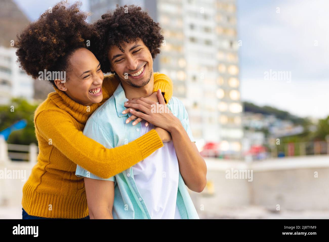 Cheerful young african american woman hugging afro boyfriend from ...