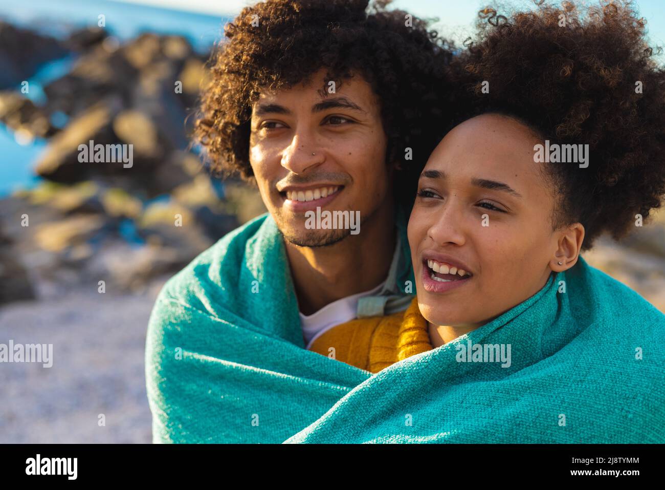 Afro african american young couple wrapped in blanket looking away at ...