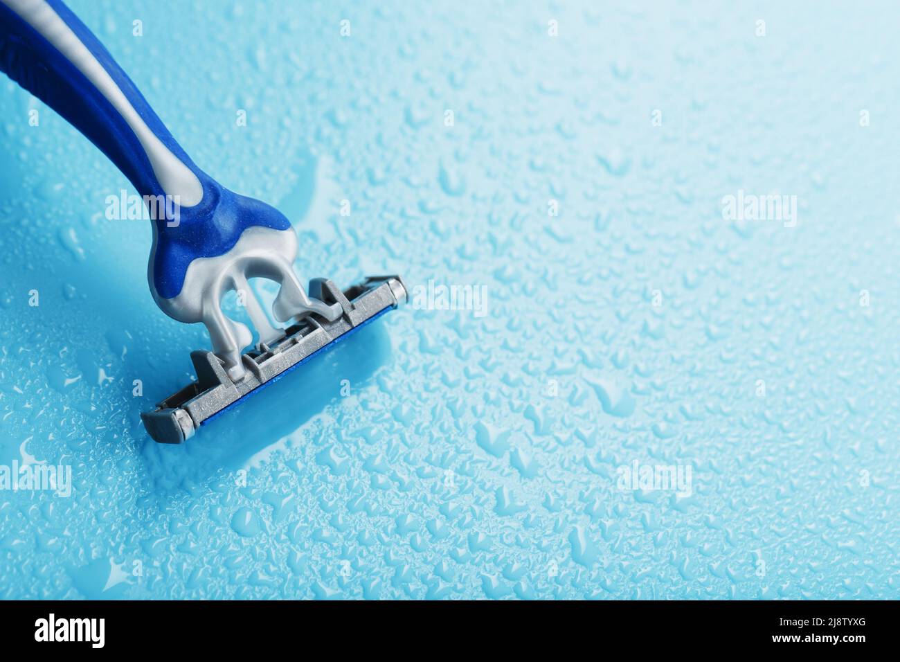Shaving machine with three blades on a blue background with water drops in close-up. The concept of purity and freshness Stock Photo
