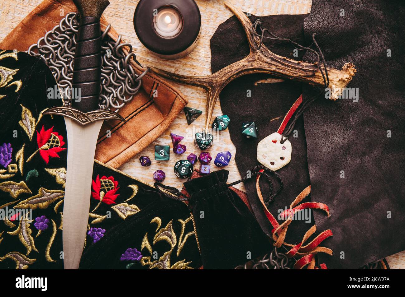 Fantasy role play board game still life concept. Background decorated with various character objects tools. Dagger, chain mail, amulet, clothing, dice Stock Photo