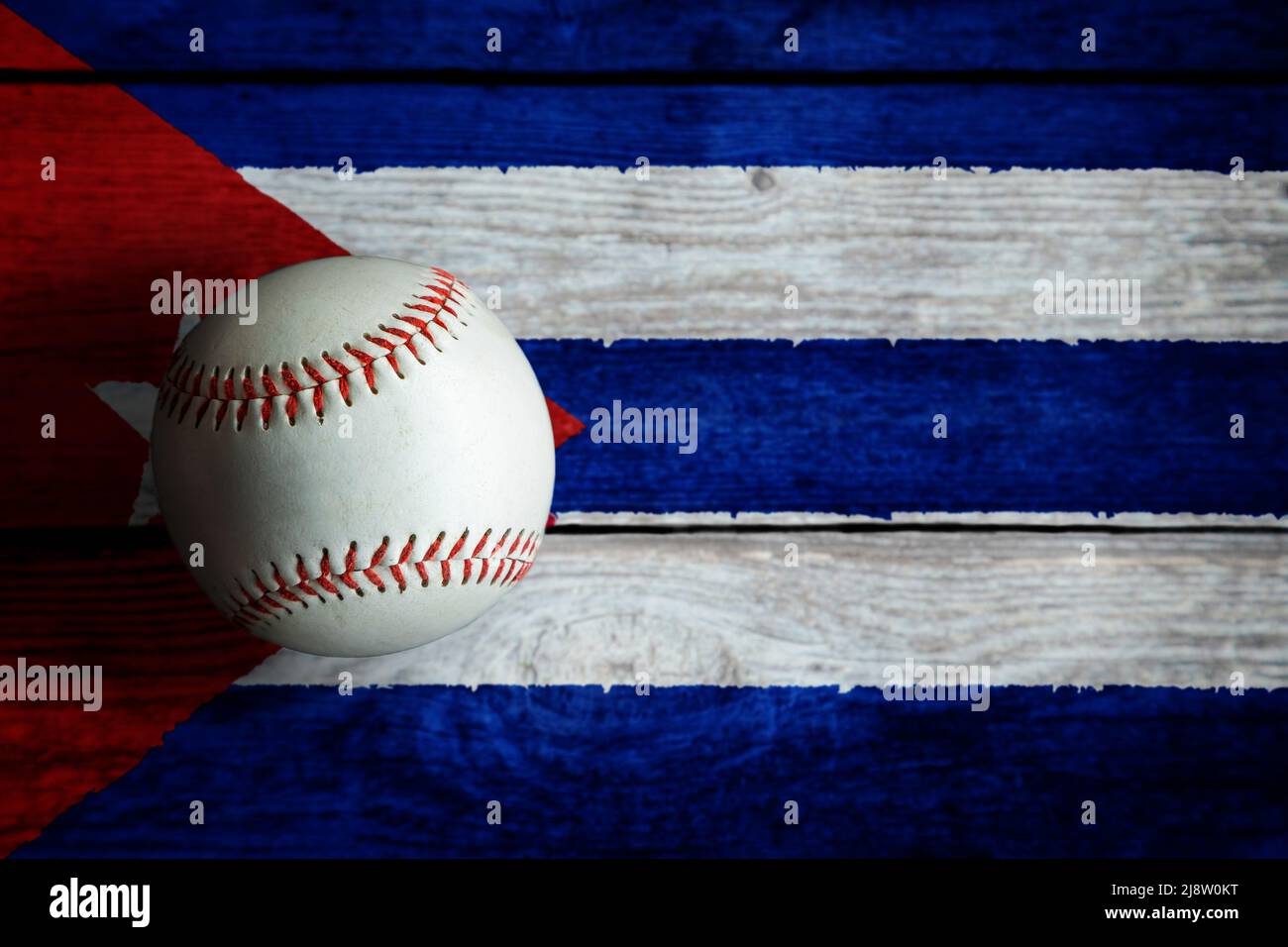 Leather baseball on rustic wooden background painted with Cuban flag with copy space. Cuba is one of the top baseball nations in the world. Stock Photo