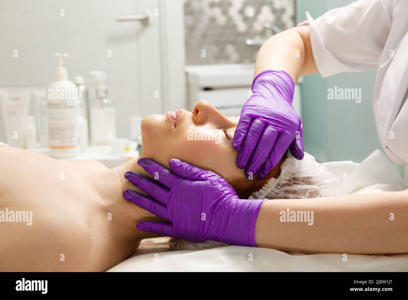 A woman gets a facial massage at a cosmetology clinic. Stock Photo