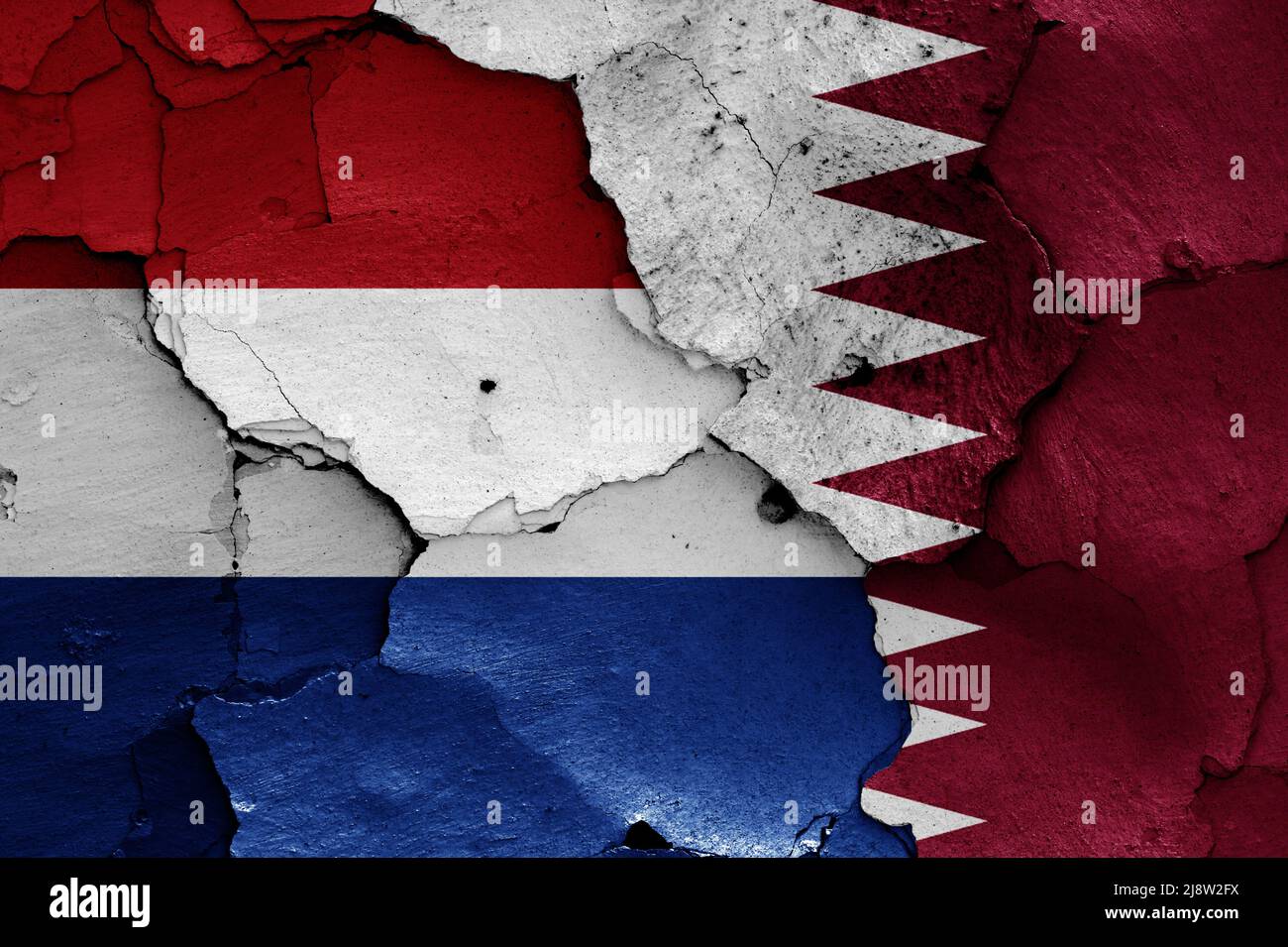 flags of Netherlands and Qatar painted on cracked wall Stock Photo