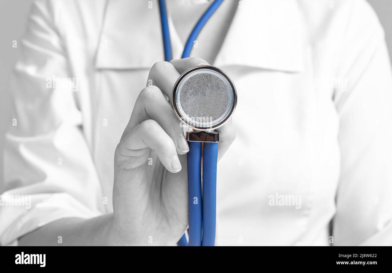 Doctor holding stethoscope for listening lungs, heart, bowel sounds. Diagnose asthma, pneumonia, cardiac problems. Woman in lab coat, hand in medical glove. Health care concept. High quality photo Stock Photo