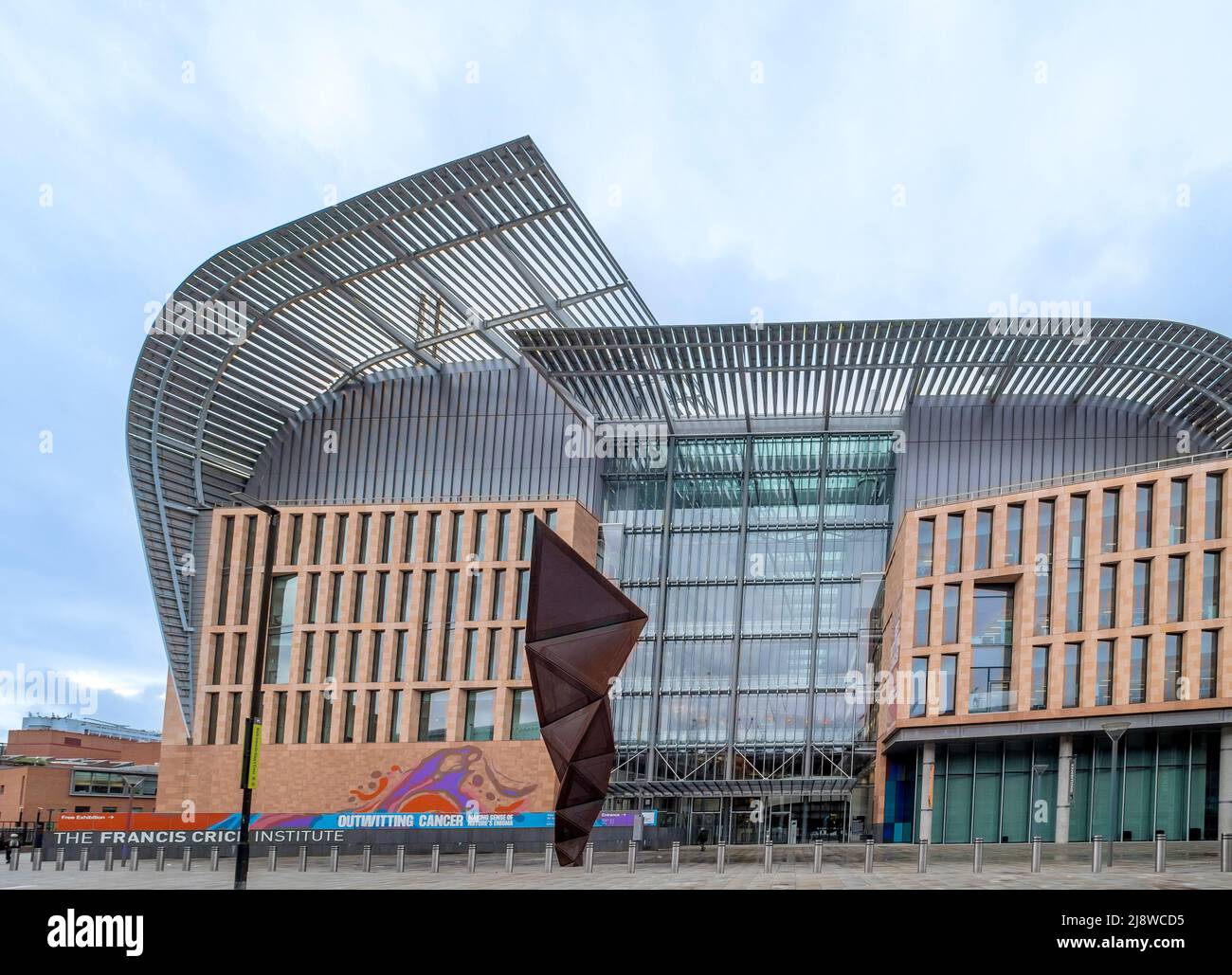 Exterior façade of The Francis Crick Institute with weathered steel Paradigm sculpture by Conrad Shawcross in the foreground. London Stock Photo