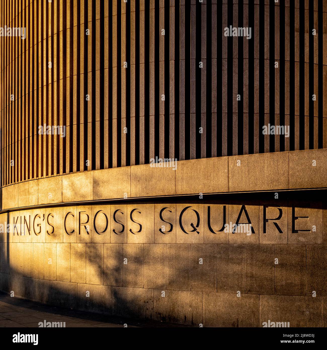 Curved kiosk façade in King's Cross Square in early morning sunlight. London. Stock Photo
