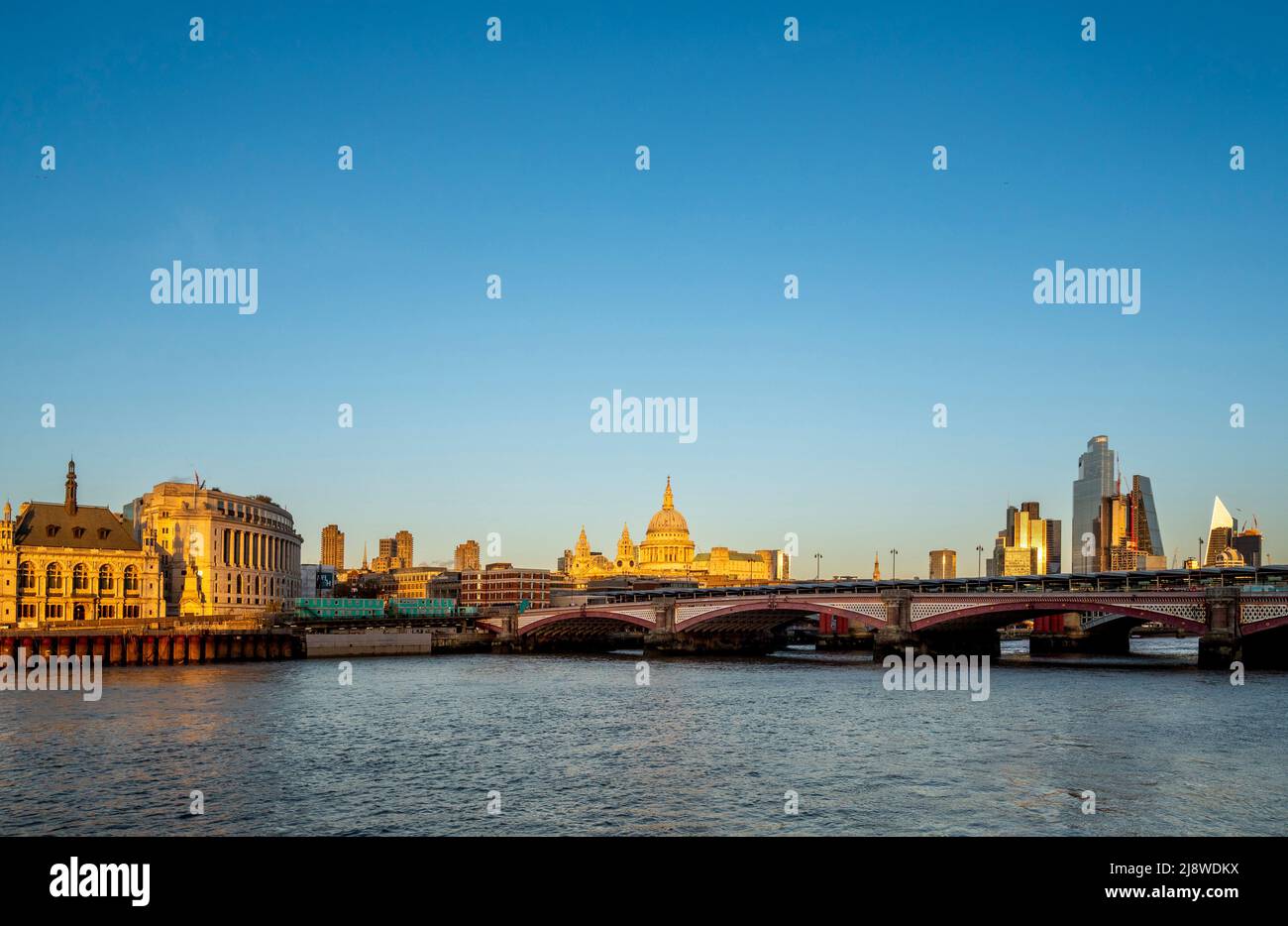 Blackfriars bridge crossing the river Thames with St Paul's Cathedral, bathed in golden late afternoon light in the distance. London UK. Stock Photo