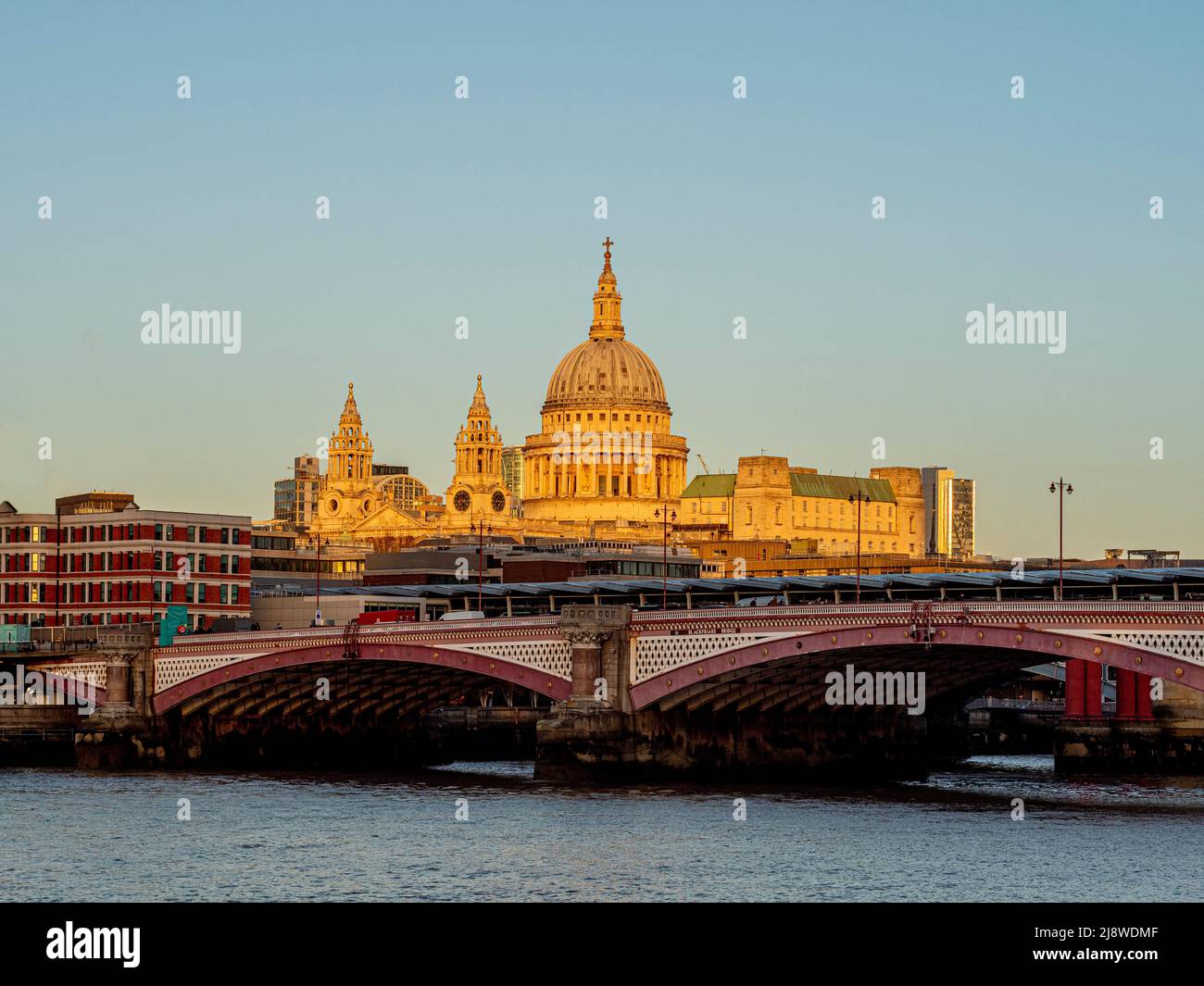 St Paul's Cathedral bathed in late afternoon sun with Blackfriars Bridge crossing the river Thames in the foreground. London. Stock Photo