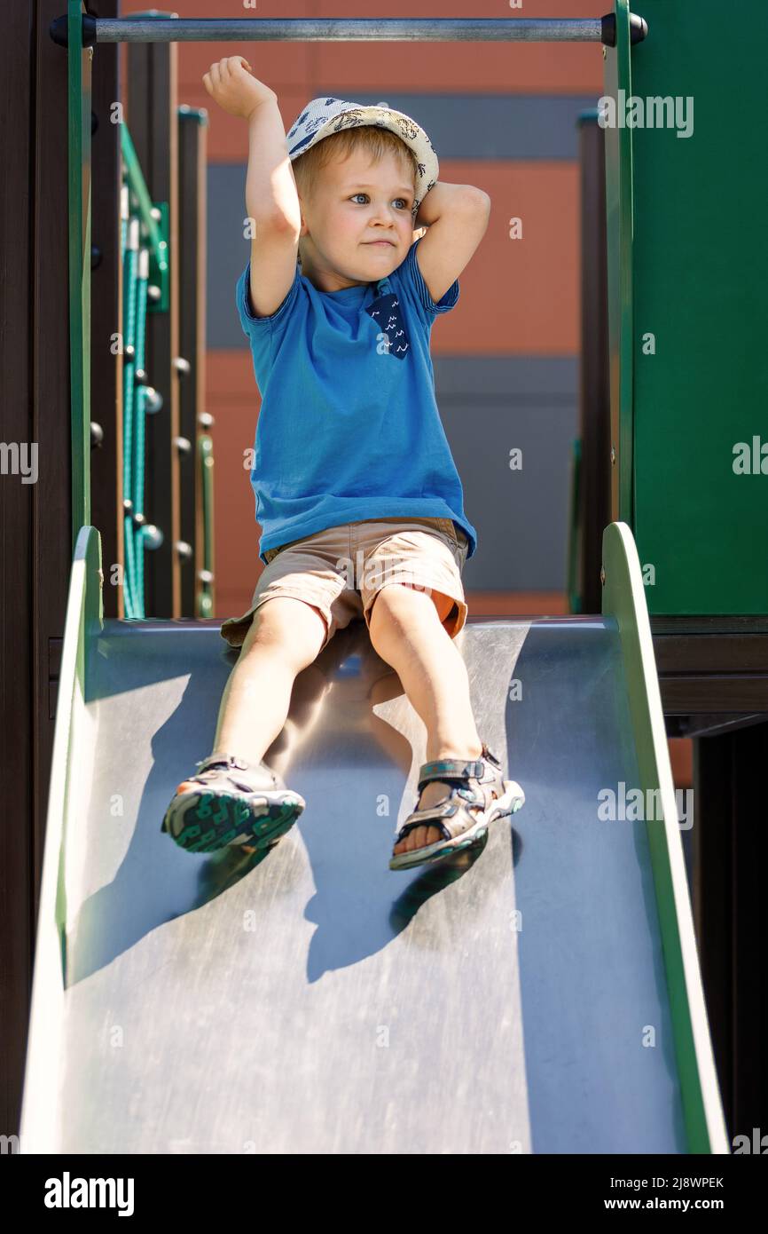 Young boy sliding down a slide in playground slide hires stock
