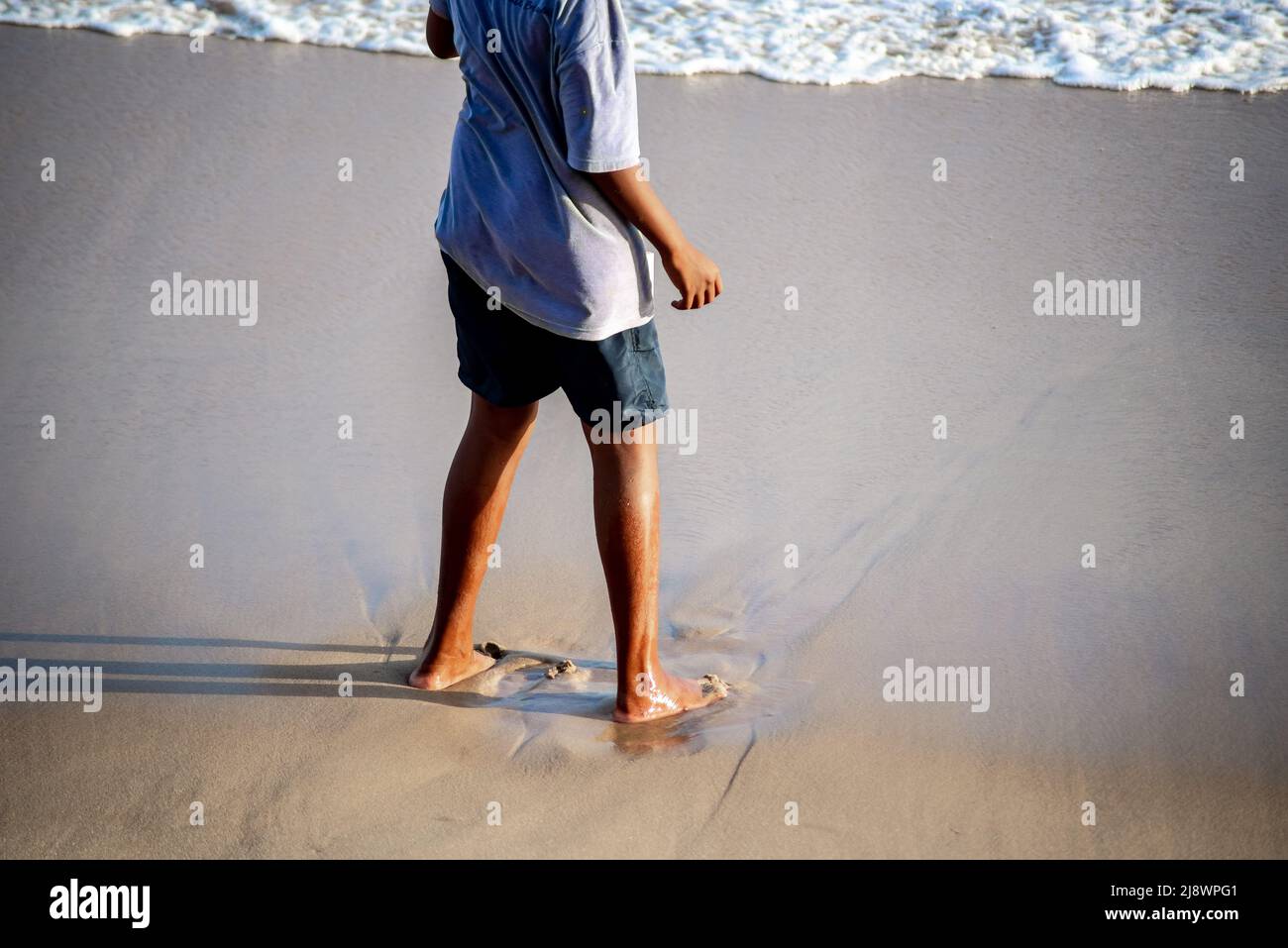Lower part of a person standing on the beach sand. Salvador city, Bahia state, Brazil. Stock Photo