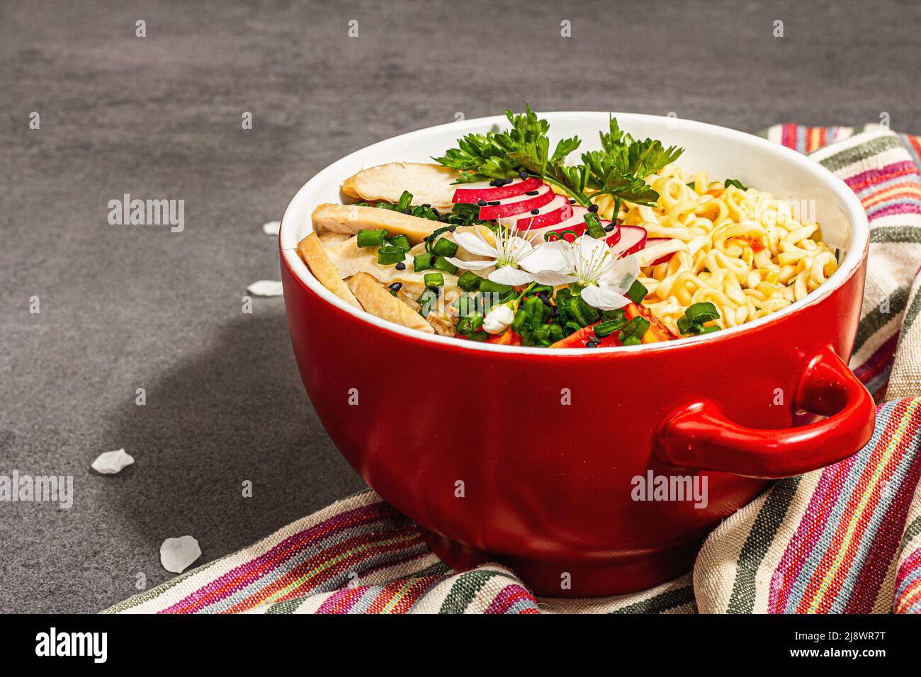 Asian noodles with chicken, vegetables, and herbs in a red bowl. Traditional Japanese soup with
