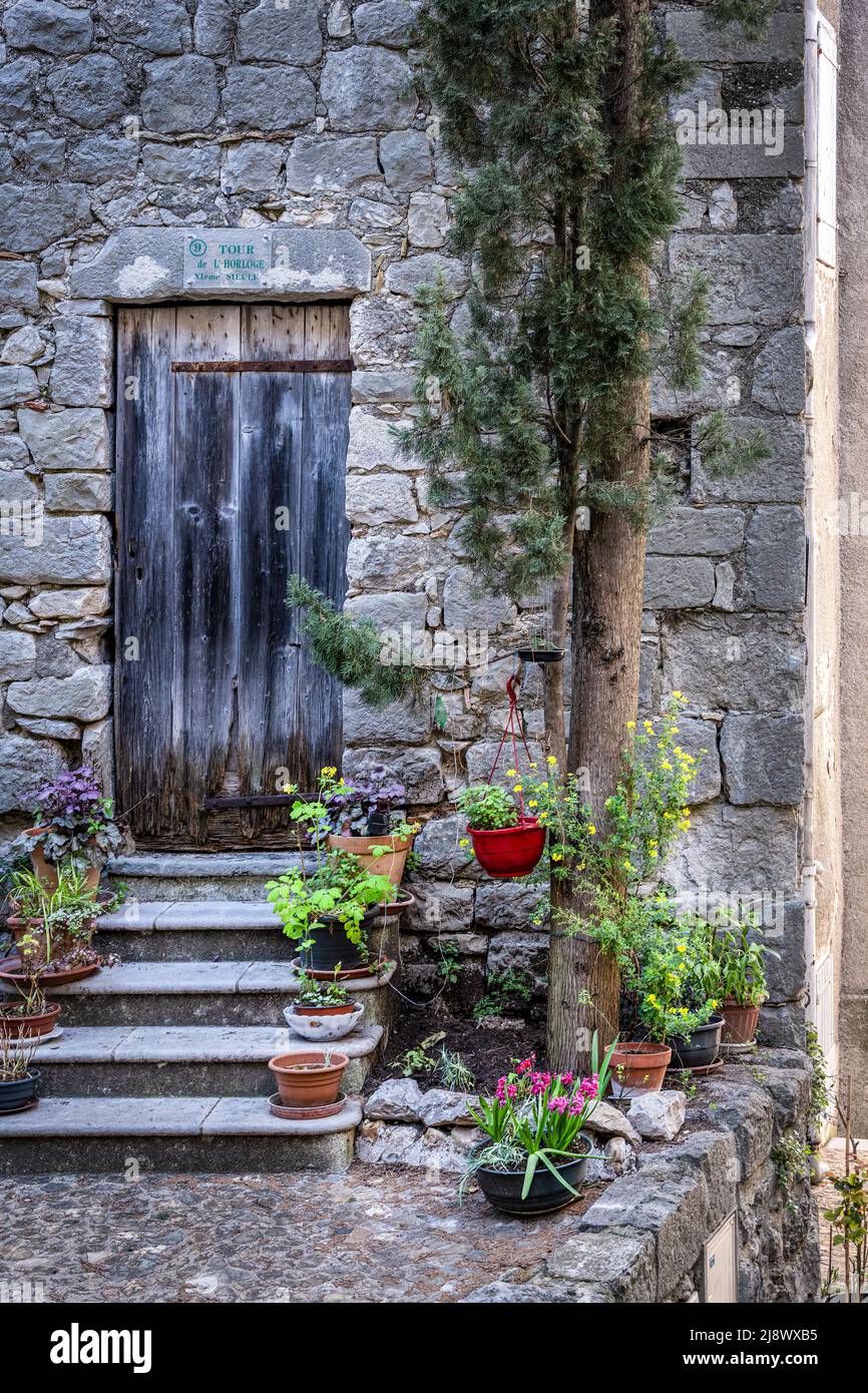 Old black wooden door in a stone wall with steps and flower pots Stock ...