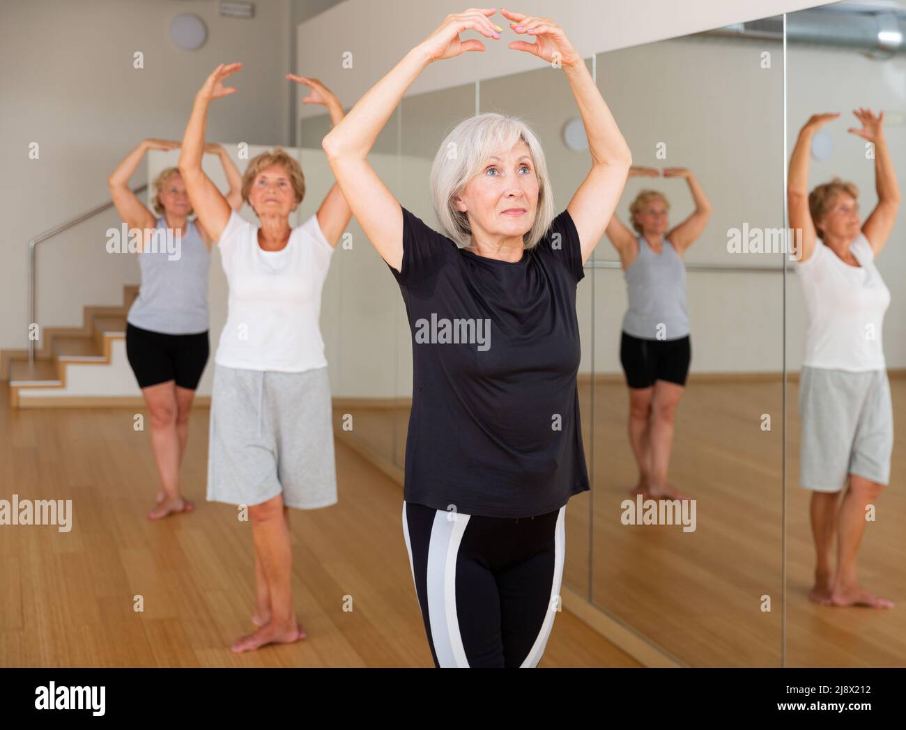 Mature woman learning classical ballet technique in choreography class Stock Photo