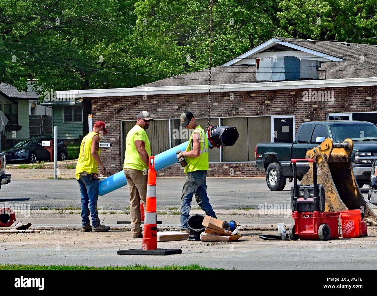 EMPORIA, KANSAS - MAY 17, 2022 As part of a weeks long project contractors prepare to lift and carry a length of blue water main pipe into place along W 6th Ave as part of an infrastructure project to replace the aging water main line that runs along that stretch of roadway Stock Photo