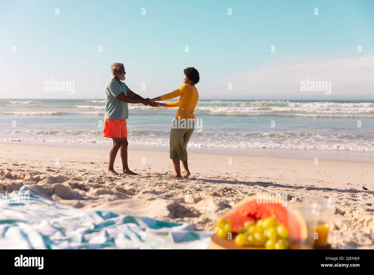African american couple holding hands and dancing on sandy beach ...
