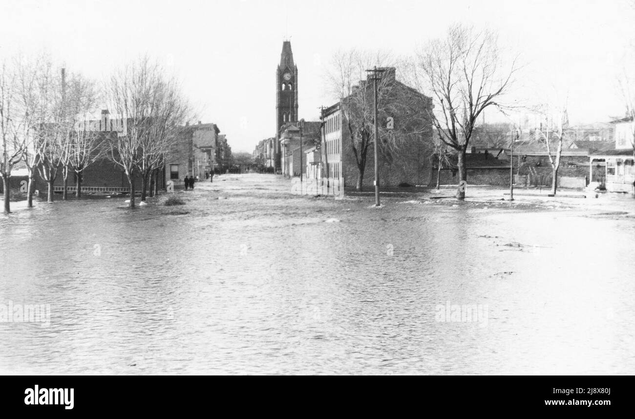 Looking up Front Street from Dundas Street in Belleville, Ontario, during the 1918 floods. City Hall is in the centre of the photograph, with the Wallbridge house  (originally Mrs. Simpson's Inn) on the extreme right  ca.  1918 Stock Photo