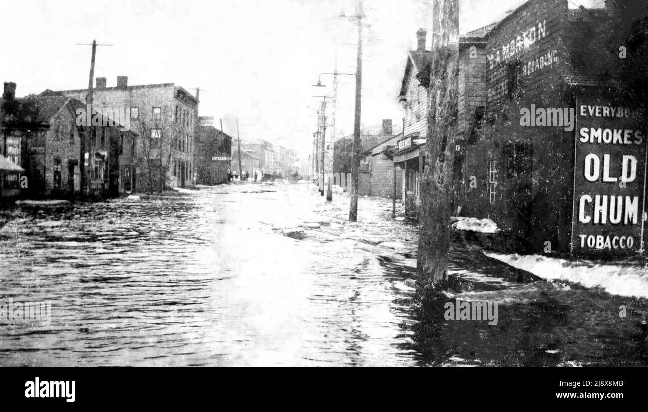 Looking east on a flooded Bridge Street West in Belleville, Ontario, during the 1918 floods. The building on the right, 21 Bridge Street West, is George Allen Morton's blacksmith shop, with a large advertisement stating Everybody smokes Old Chum tobacco.  The three-storey building on the left is the Windsor Hotel on the northwest corner of Bridge and Coleman Streets  ca.  1918 Stock Photo