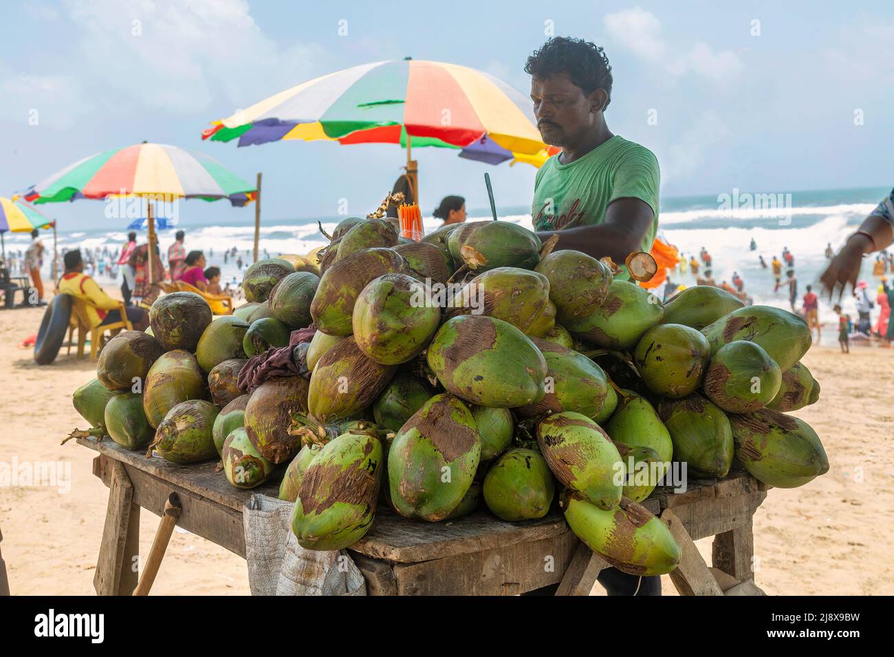 Man selling coconut water on the sea beach at Puri Odisha, India Stock Photo