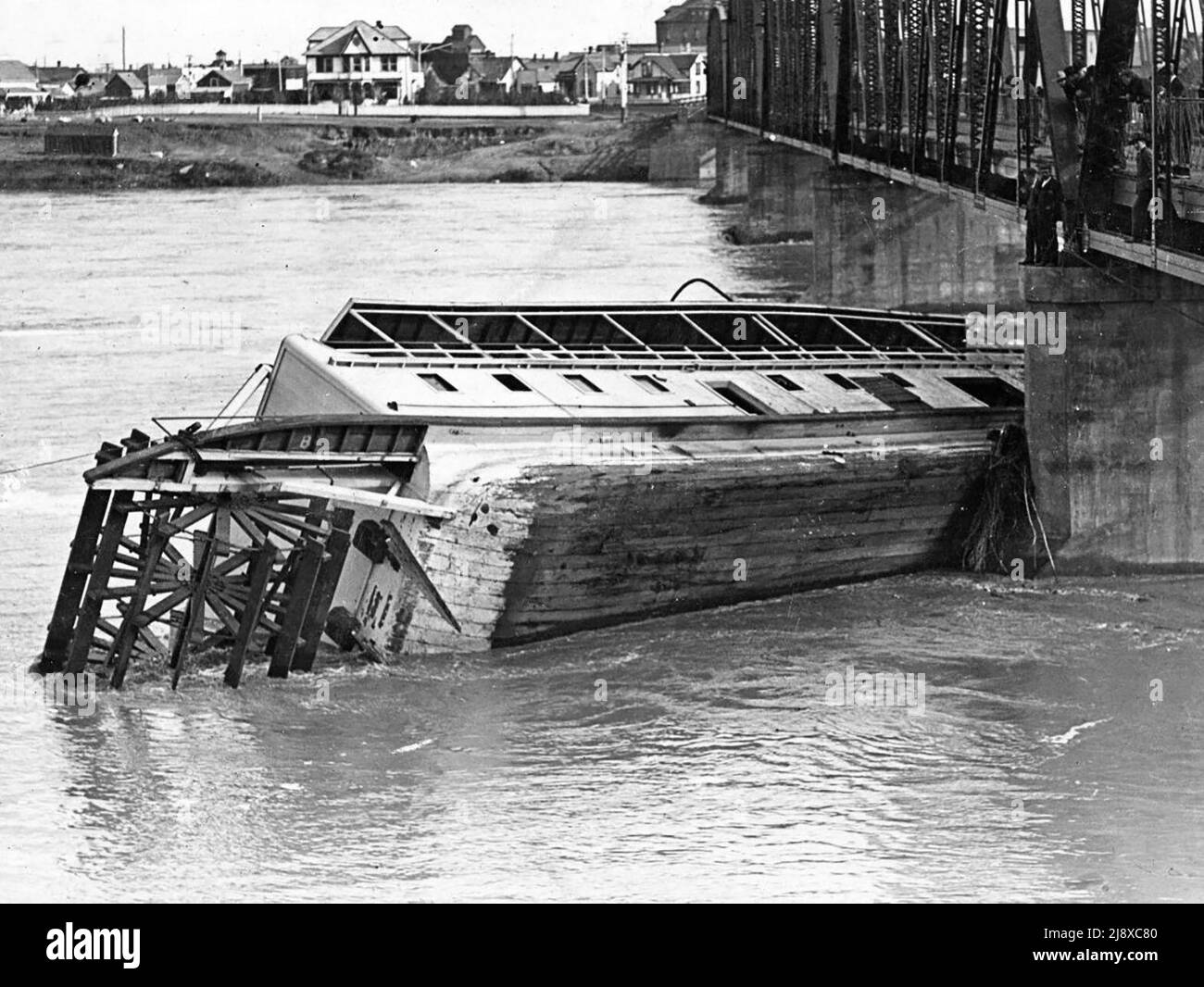 Wreck of the paddlewheel steamship SS City of Medicine Hat against the Traffic Bridge in Saskatoon, Saskatchewan, Canada  ca.  1908 Stock Photo