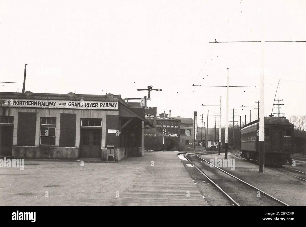 Station & car at Galt (1 mi. from CPR station)  This photo  taken on 20 April 1947, shows the joint Grand River Railway/Lake Erie and Northern Railway station at Main Street in Galt, Ontario, Canada, with an unidentified interurban car to the right. In the centre of the photograph, some evidence of Galt's industrial operations at the time is visible in the background Stock Photo