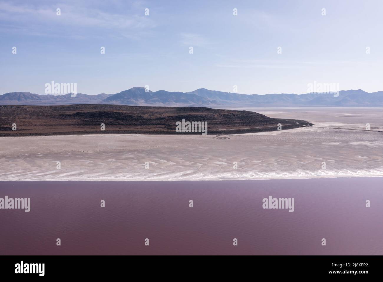 Pink Lake at Great Salt Lake in Utah. Spiral Jetty on arid beach. Stock Photo