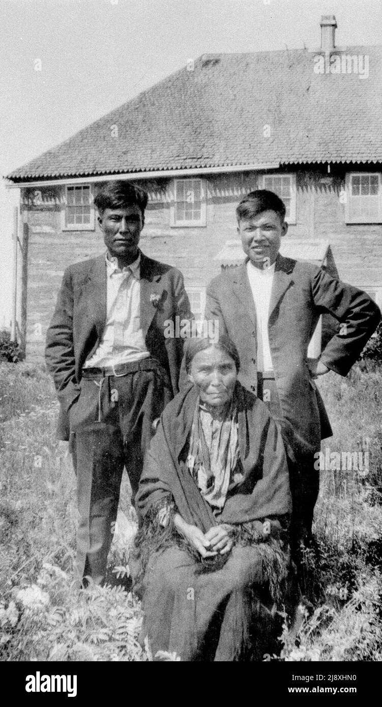 Mary Ann Koketta, a Dene (likely South Slavey) woman sitting with two men behind herPhoto taken at Fort Simpson, N.W.T.  ca.  1931 Stock Photo