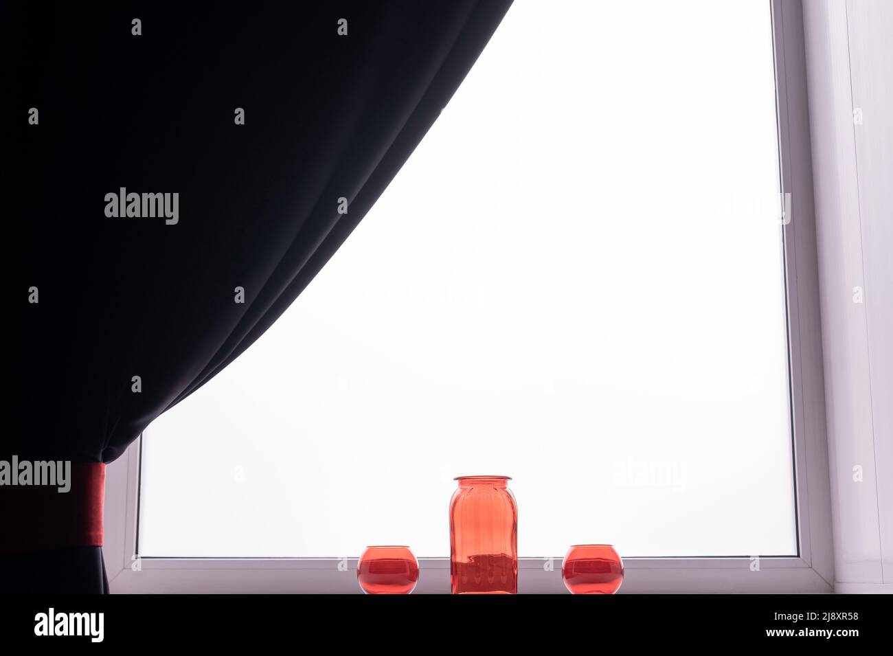 Three empty glass red vases on the windowsill.  Stock Photo