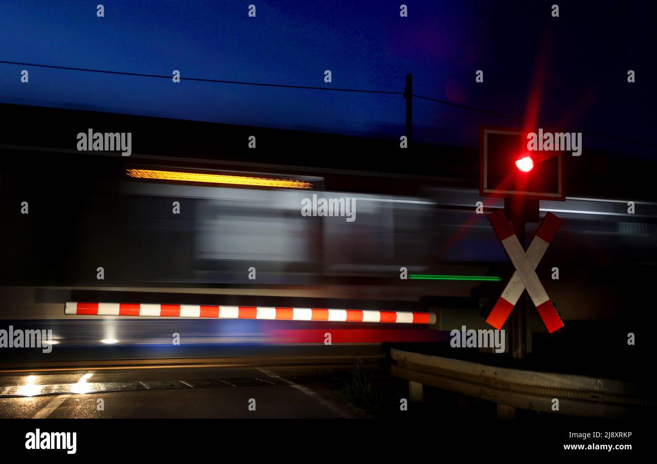 Ebenhofen, Germany. 19th May, 2022. Early in the morning, a regional train passes behind a red light at a level crossing with a barrier. Credit: Karl-Josef Hildenbrand/dpa/Alamy Live News Stock Photo