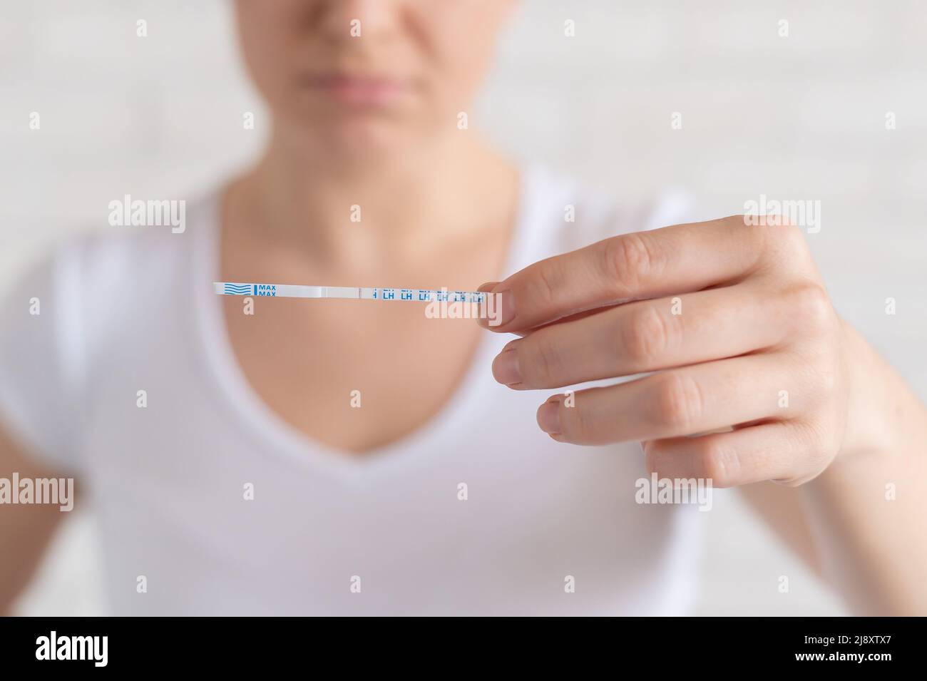 Sad woman shows a negative ovulation test. The concept of female infertility and low luteinizing