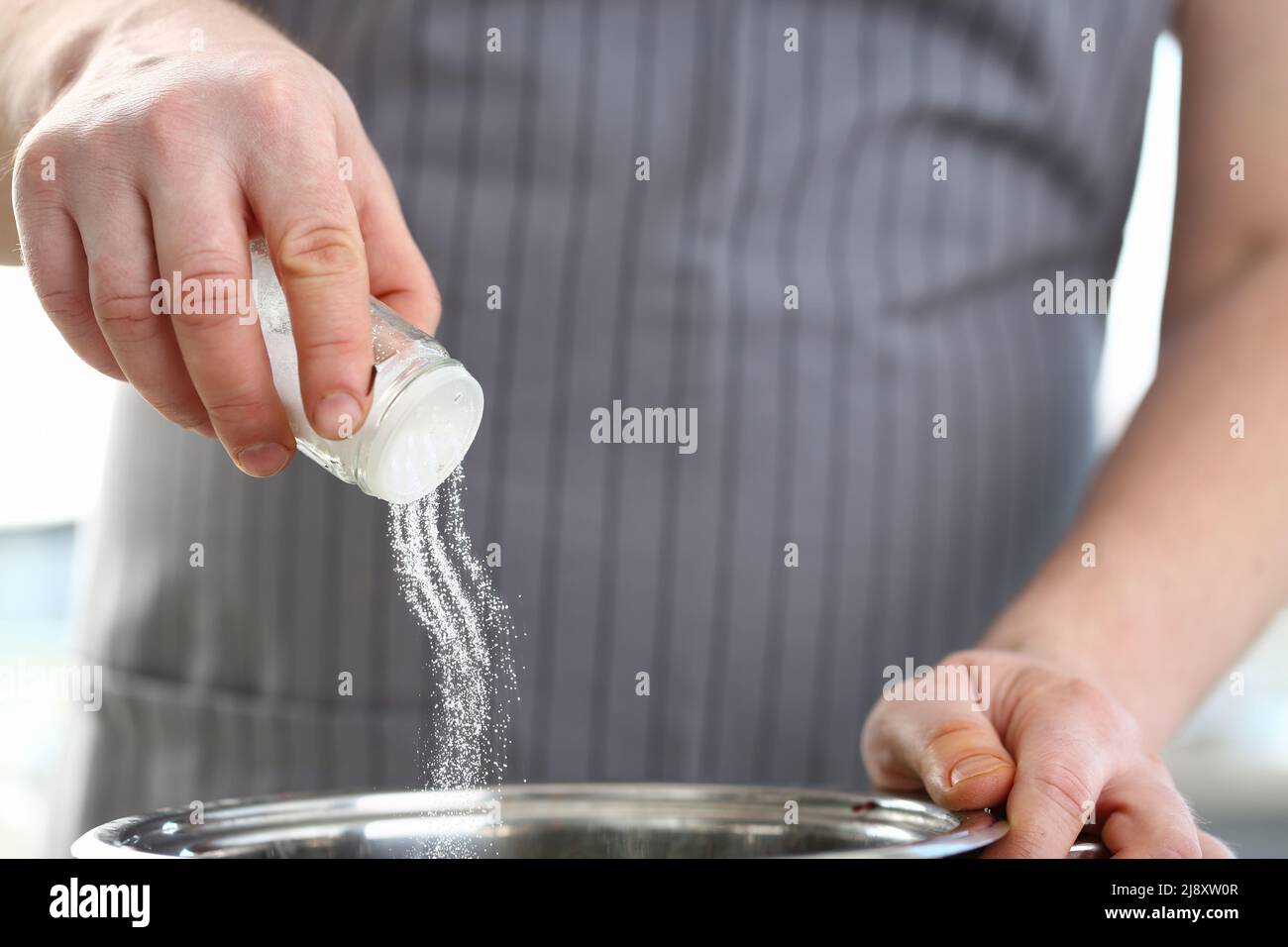 Professional cook hold saltcellar and add salt to soup, chef follow ...