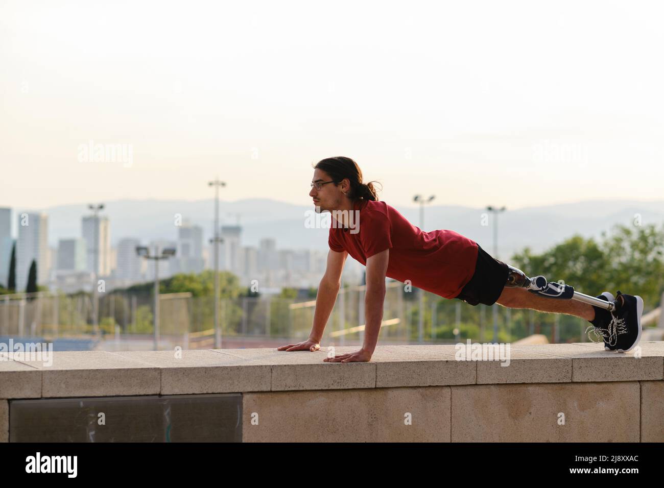 Young male athlete with a disability doing push ups while exercising outdoors. Stock Photo