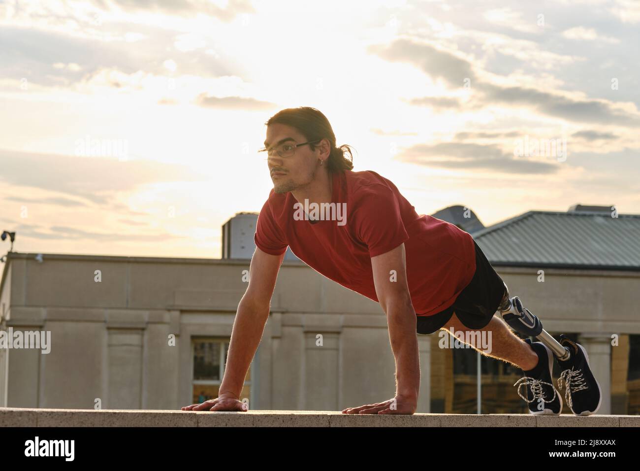 Sporty man with a disability doing push-ups while exercising outdoors. Stock Photo