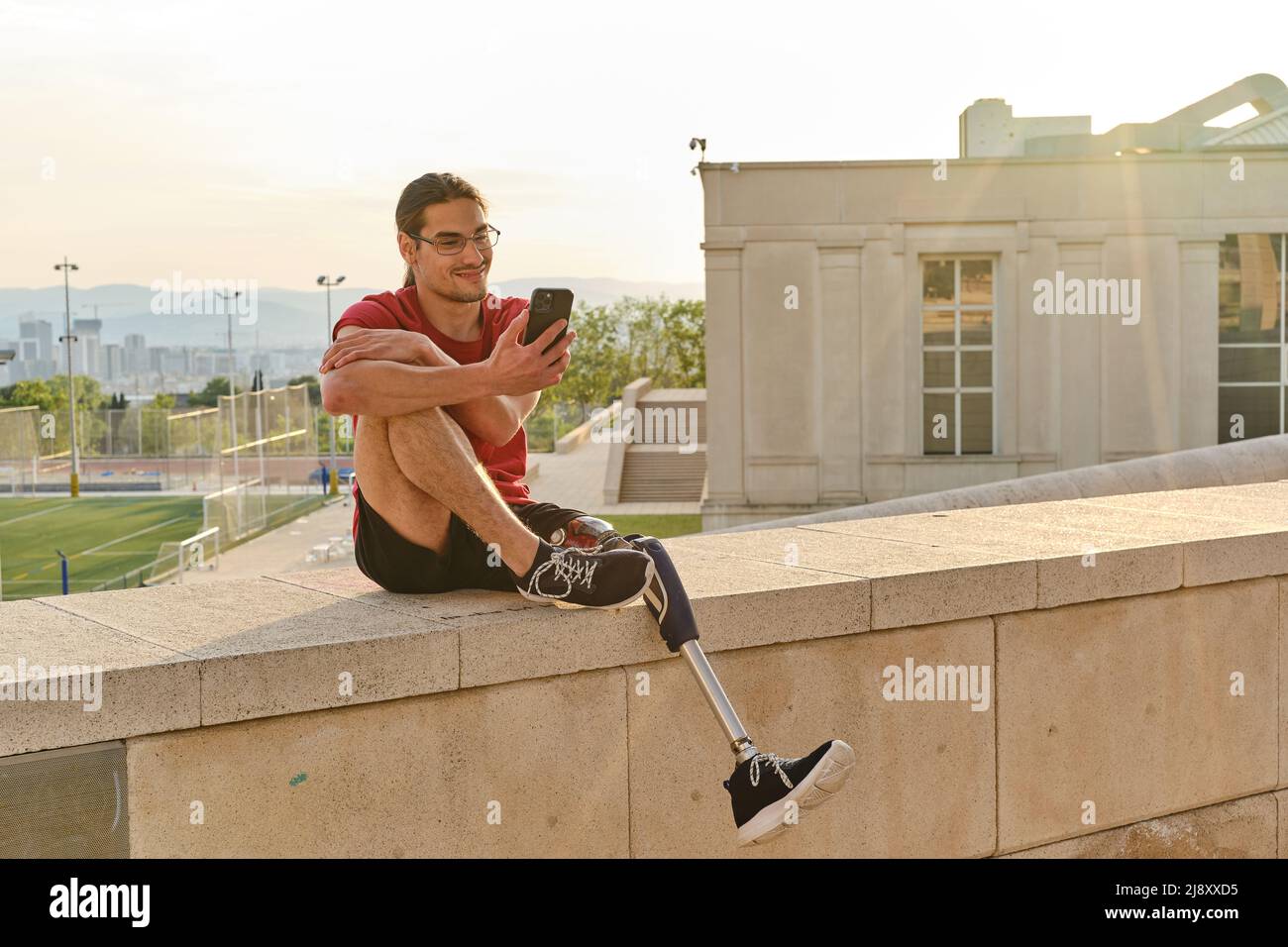 Man with a disability using his smartphone while sitting outdoors. Stock Photo