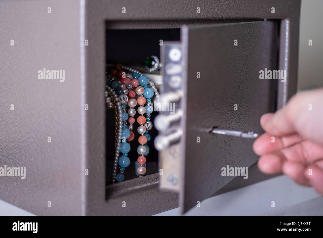 Money and jewelry in an open safe on the table. There is money and beads in the open safe. Stock Photo