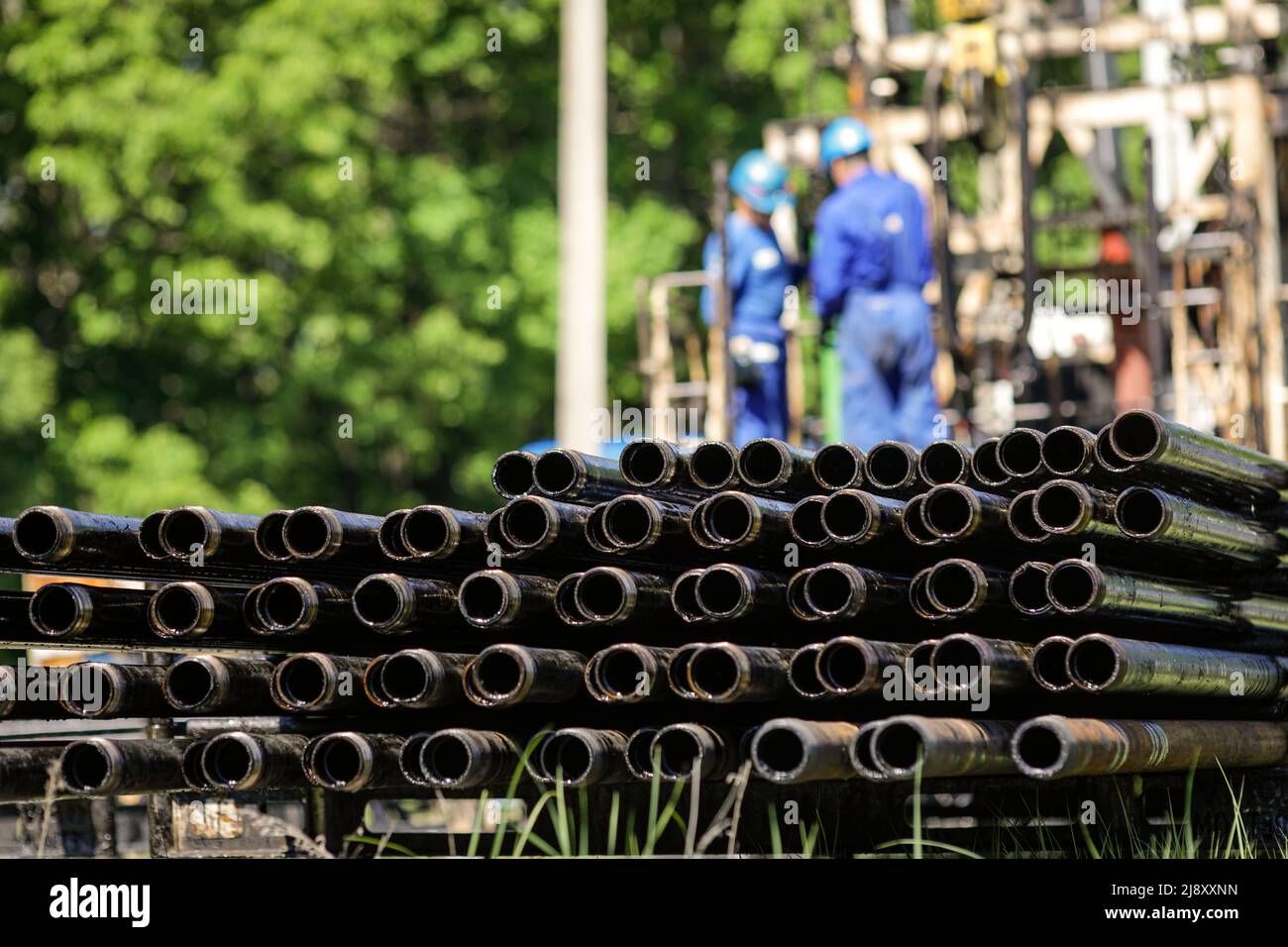 Oil rig drill pipes stacked with oil industry workers in the background