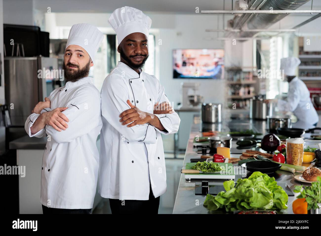 Multiethnic male cooks standing in restaurant professional kitchen with ...